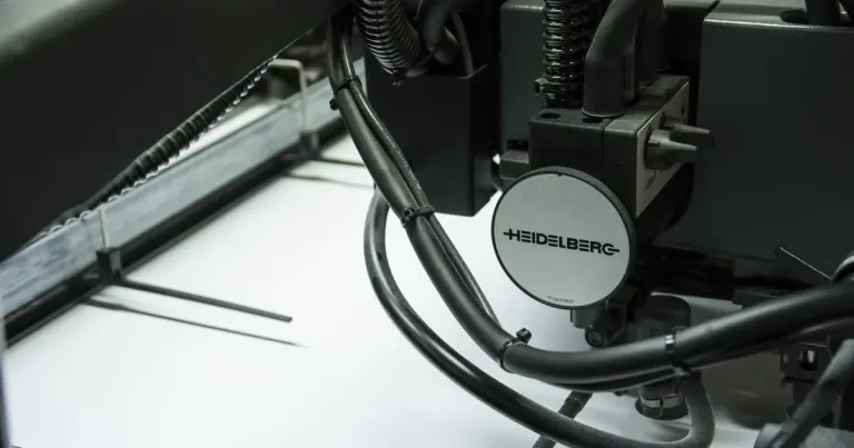 Producción gráfica contemporánea en una máquina Heidelberg Máquina de impresión moderna Heidelberg trabajando sobre papel en una instalación gráfica.